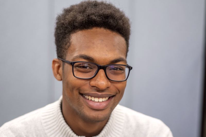 Smiling person wearing glasses and sweater